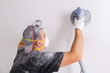 © Patryk Kosmider - Plasterer wearing dust mask polishes a wall with sanding machine . House renovation concept.