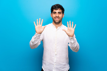 Wall Mural - Young man over isolated blue wall counting ten with fingers