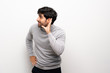 © luismolinero - Young man over isolated white wall listening to something by putting hand on the ear