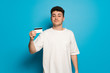 © luismolinero - Young man over blue background holding a credit card