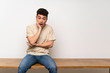 © luismolinero - Young man sitting on table surprised and shocked while looking right