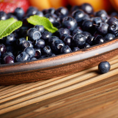 Wall Mural - Clay plate full of Ripe organic blueberries on wooden table