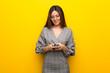 © luismolinero - Young woman with glasses over yellow wall sending a message with the mobile