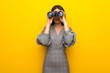 © luismolinero - Young woman with glasses over yellow wall and looking in the distance with binoculars