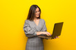 © luismolinero - Young woman with glasses over yellow wall with laptop