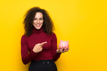 Wall Mural - Dominican woman with turtleneck sweater holding a piggybank