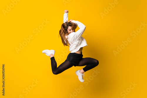 Fotografía Young woman jumping over isolated yellow wall