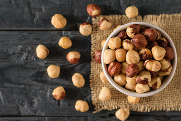 Scattered on the table roasted hazelnuts on a black wooden table. Prepared with the harvest of hazelnuts. Flat lay.
