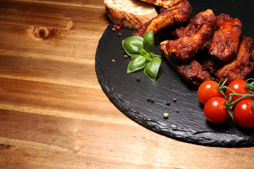 Spicy hot grilled spare ribs from a summer BBQ served with fresh tomatoes on an vintage cutting board