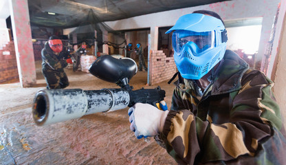 Wall Mural - Portrait of blue team player who is aiming in opponents on paintball field.