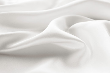 white silk texture. background of white fabric lying folds on the table