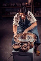 Wall Mural - Beautiful young lady making pottery, sculptor from wet clay on wheel. Handicraft production.