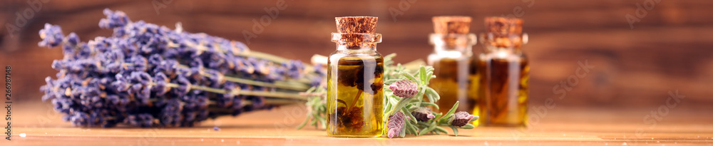 essential lavender oil in a glass bottle on a background of fresh flowers - obrazy, fototapety, plakaty 