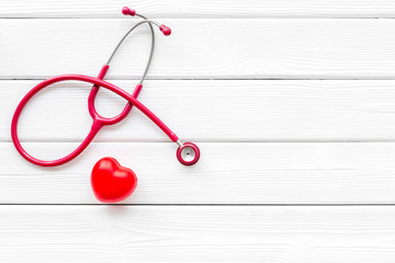 Wall Mural - diagnostic and cure of cardiac disease with stethoscope and heart on white wooden background top view mock-up