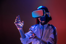 Excited Young Woman Touching Air While Having Virtual Reality Experience In Neon Light
