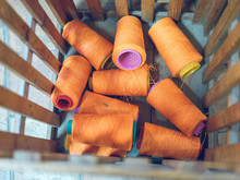Bunch Of Spools With Orange Thread Placed Inside Wooden Container On Factory