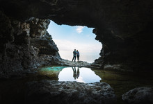 Young Couple Stand Together At The Mouth Of A Grotto