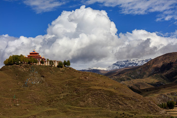 Buddhist Temple on the top of a hill, Tibetan Village of Bamei situated in the grasslands of Sichuan Province, China. blue sky white clouds in the distant background. Tagong and Xinduqiao scenery