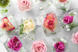 Ice cubes with flowers on marble background, flat lay