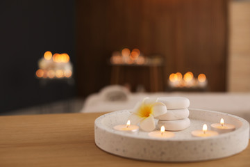 Sticker - Beautiful composition with burning candles and spa stones on table in salon. Space for text