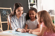 © New Africa - Cute little children with nursery teacher reading book at table in kindergarten. Indoor activity
