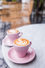 Wall Mural - Two pink cups of cappuccino with beautiful latte art on marble table background. Cafe backdrop.