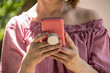 © Susan Vineyard  - Close-up of woman holding and reading from a cell phone in pink case with grip handle on back  -  off shoulder blouse and short hair - selective focus and unrecognizable