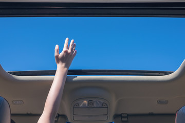 girl driver traveling by car and holds her hand out from open hatch of a vehicle. Travel lifestyle concept