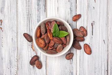 Wall Mural - Cocoa beans in bowl with green leaves