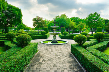 Sleepiness fountain in middle of crushed rock road are luxury garden in Bangkok, Thailand. This line of crushed rock road go straight to fountain concept,  forest and blue sky in a background.