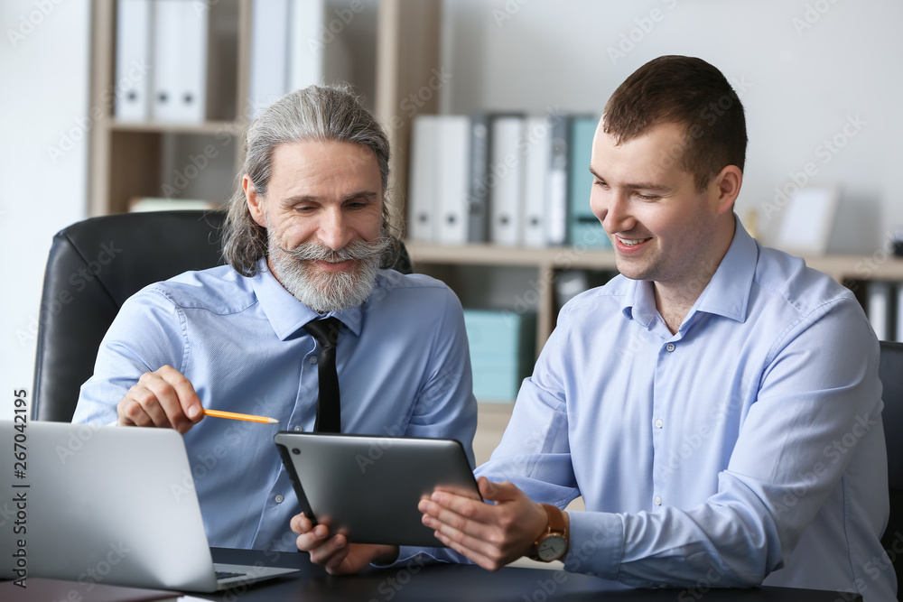Mature businessman working with young colleague in office