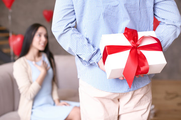 Young man hiding present for his wife behind back