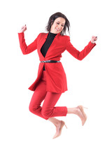 Wall Mural - Cheerful young business woman in red dress jumping in mid air looking down. Full body isolated on white background.