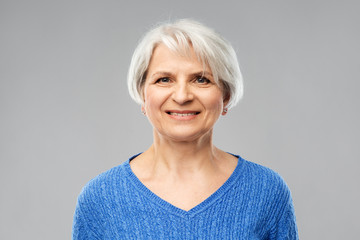 Wall Mural - old people concept - portrait of smiling senior woman in blue sweater over grey background