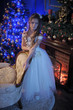 Girl in white dress in the fireplace on background glowing Christmas tree.