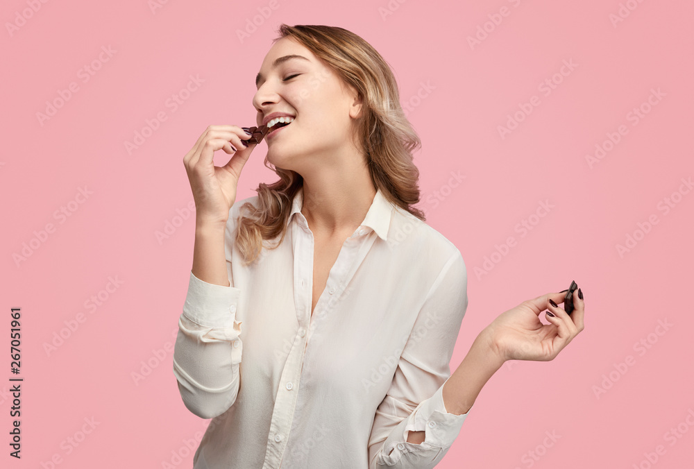 Young woman eating chocolate with closed eyes - obrazy, fototapety, plakaty 