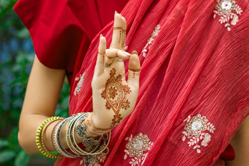 Wall Mural - Beautiful woman in traditional Muslim Indian wedding pink red sari dress with henna tattoo jewelry bracelets do hands nritta odissi Samyuta Hasta Mudras dance Movement tripataaka Concept background