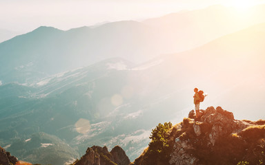 Wall Mural - mountain hiker with backpack tiny figurine stay on mountain peak with breathtaking hills panorama