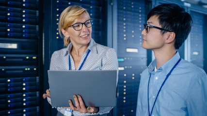 Aufkleber - In the Modern Data Center: Engineer and IT Specialist Walking alongside Server Racks, Talking, Doing System Maintenance Check with Laptop Computer. Specialists Doing Diagnostics of the Database.