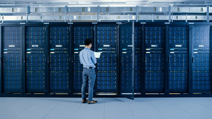 Poster - In the Modern Data Center: IT Engineer Standing Beside Open Server Rack Cabinets, Does Wireless Maintenance and Diagnostics Procedure with a Laptop.