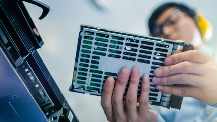 Fototapete - In the Data Center: IT Engineer Installs New HDD Hard Drive and Other Hardware into Server Rack Equipment. IT Specialist Doing Maintenance, Running Diagnostics and Updating Hardware. Low Angle.