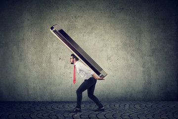 Young business man struggling to carry huge smartphone