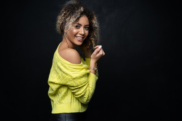 Wall Mural - Portrait of a beautiful black female fashion model with curly hair over black background.