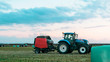 Agricultural work in a field at sunset. Equipment for forage. Film wrapping system. Round bales of feed for farm animals.