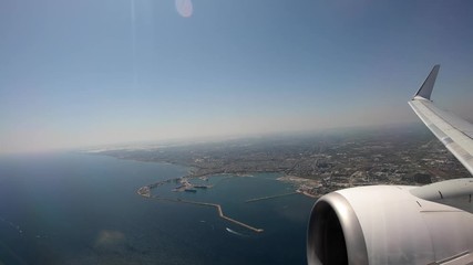 Wall Mural - 4K, Aerial view bay of Bari. Beautiful landscape of beach and blue ocean from the plane during the flight. Airplane wing with mediterranean sea and big city -Dan