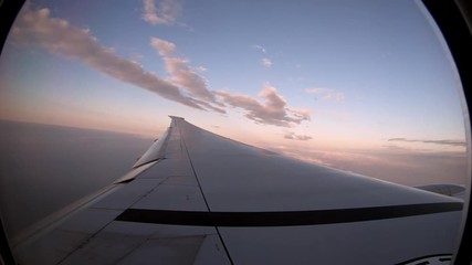 Wall Mural - 4K, Beautiful clouds from above, as seen through airplane window. Traveling by air. View of traveler in cabin at turbine and plane wing in flight trip with beautiful blue sky. -Dan