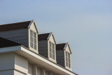 Poster - perspective view of modern gable roof design house wall with evening sky background.