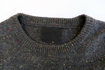 Clothing label inside of gray sweater. Black label on a men's knitted sweater.