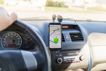 Arrival or destination point on the map in the phone on the dashboard background. Black mobile phone with GPS map navigation is fixed in the installation. App map for traveling with route