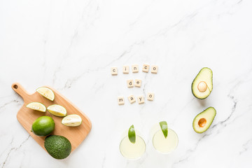 Wall Mural - Fresh avocado, lime, drink and nacho chips lying on marble background. Recipe for Cinco de Mayo party. Top view, overhead, flat lay, copy space